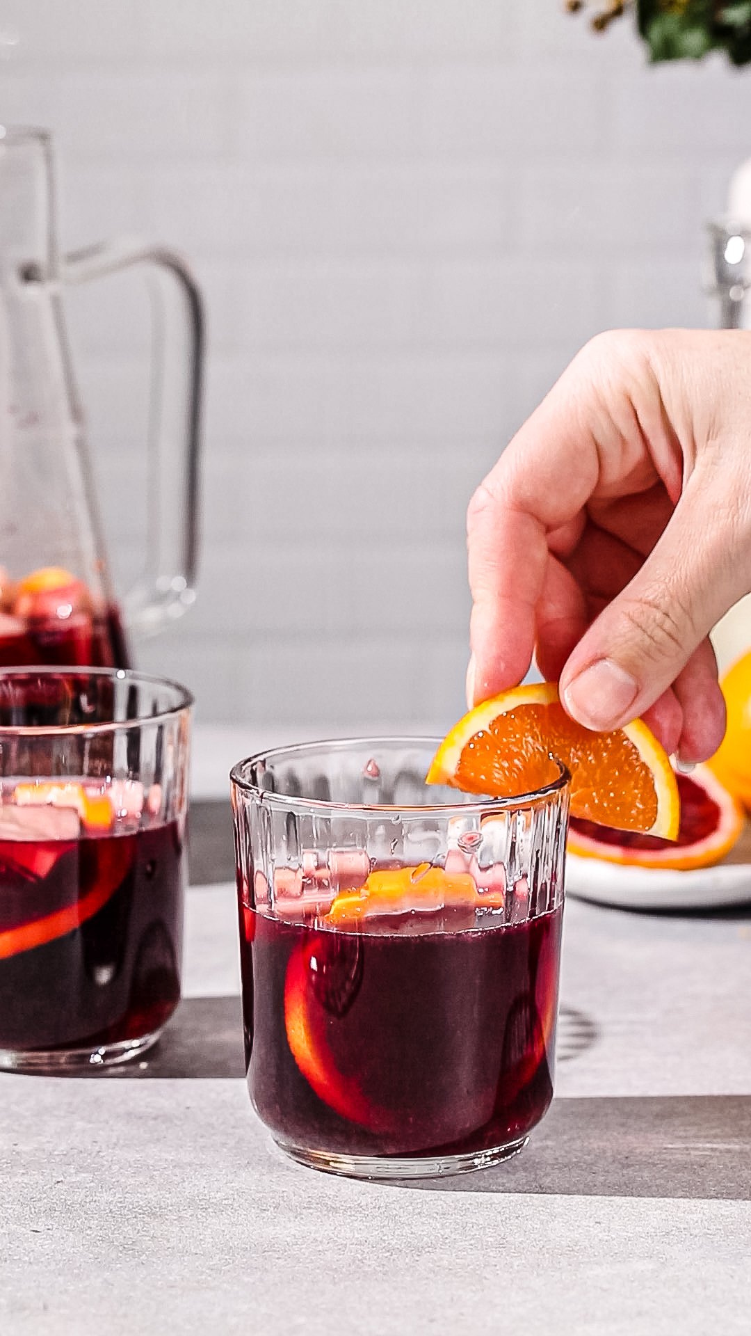 Hand adding a slice of orange to the rim of a glass of sangria.