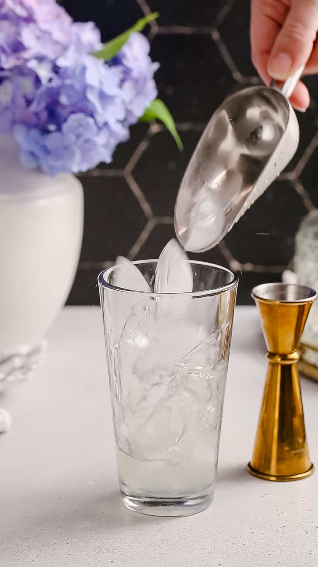 Ice being added to the cocktail shaker glass.