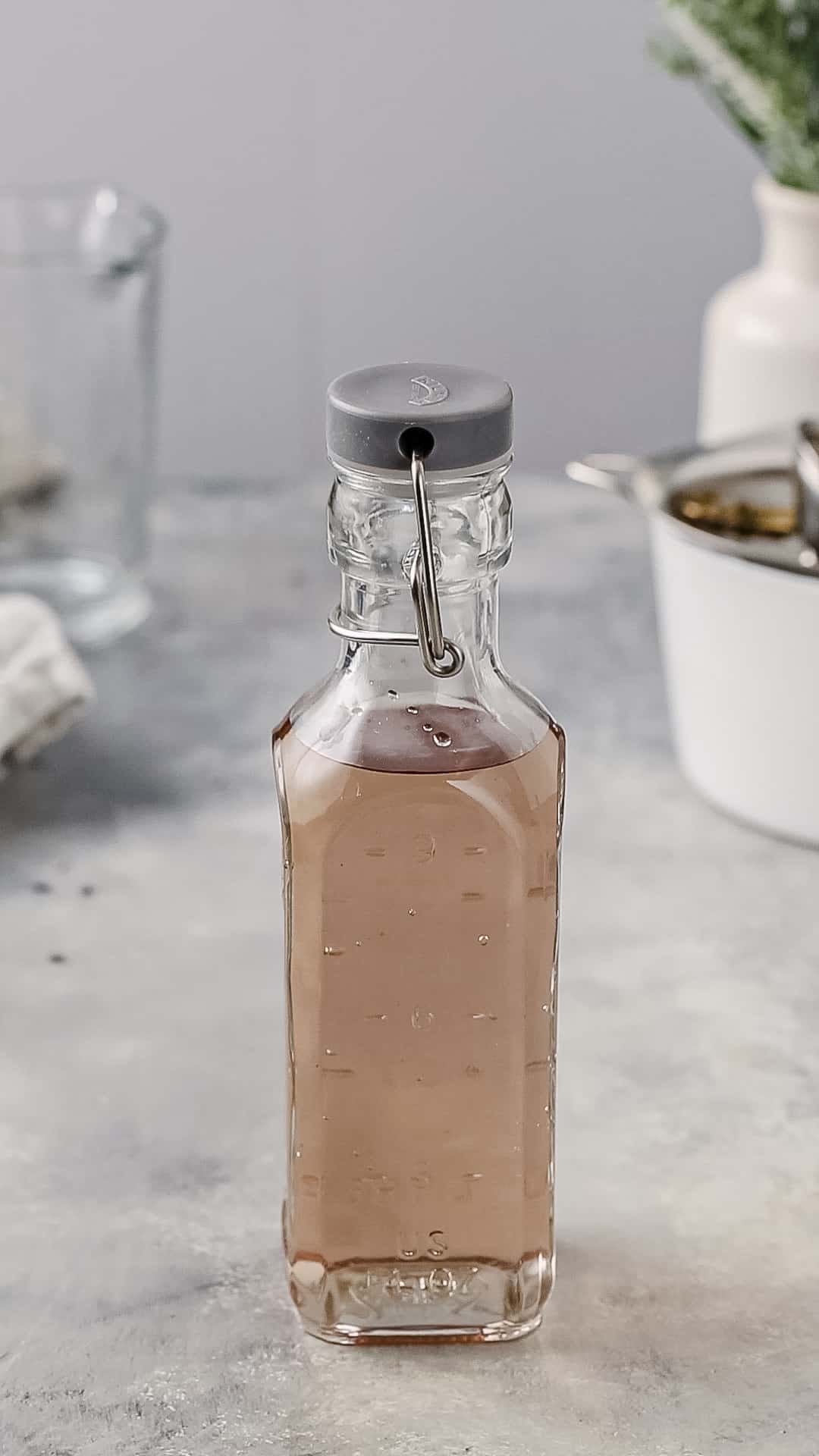 Lavender syrup in a sealed glass bottle on a countertop.