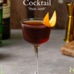 Side view of brown colored Tipperary cocktail with an orange peel garnish. Green vines overlay on the bottom of the image and overlay text says "tipperary cocktail" on the top.