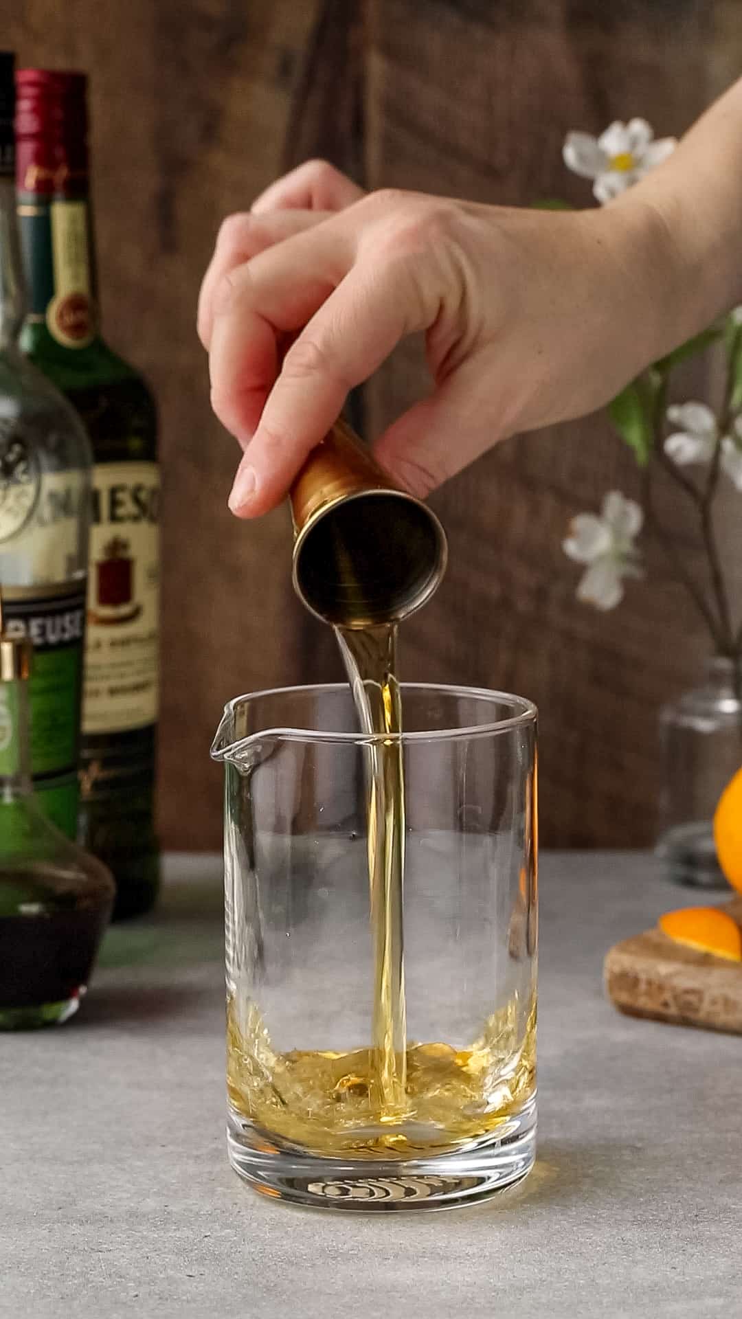 Whiskey is being added to a heavy bottomed cocktail mixing glass.