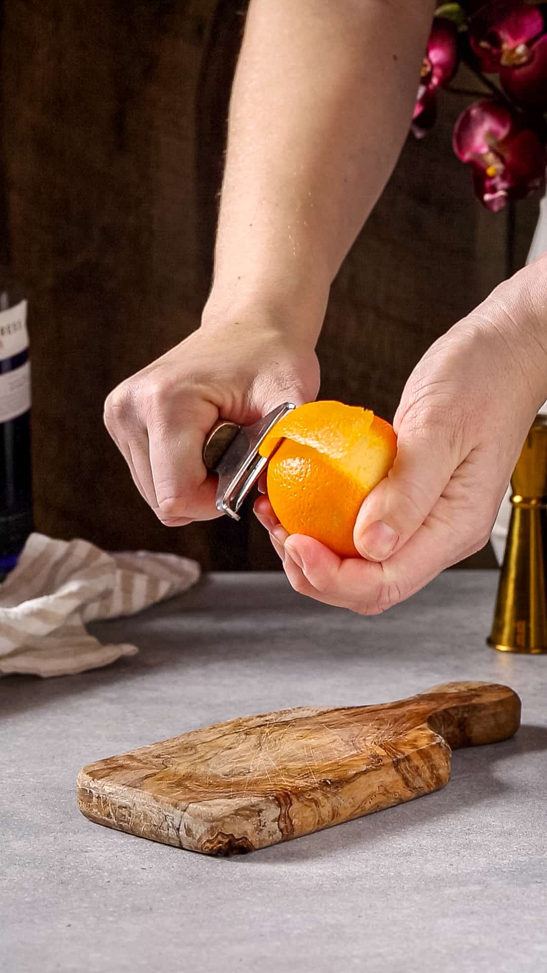 Peeling a large orange with a fruit peeler.