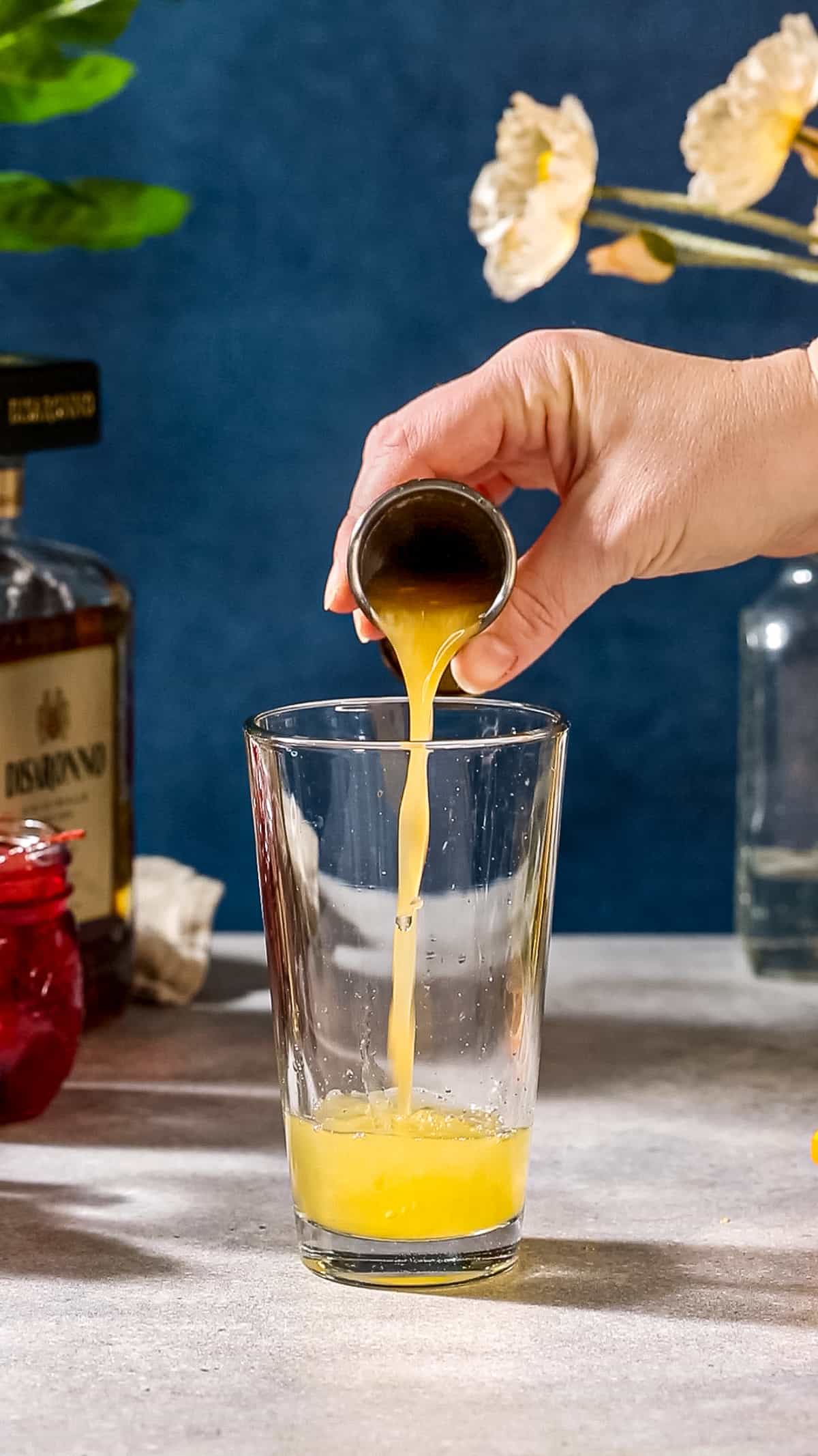 Pouring the orange juice into the cocktail shaker glass.