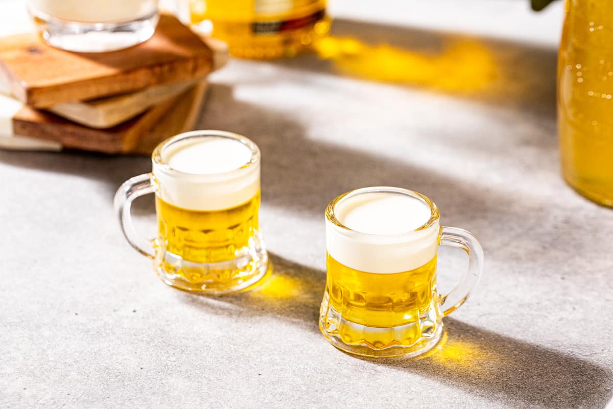 Two layered yellow and white mini beers shots sitting side by side on a countertop.
