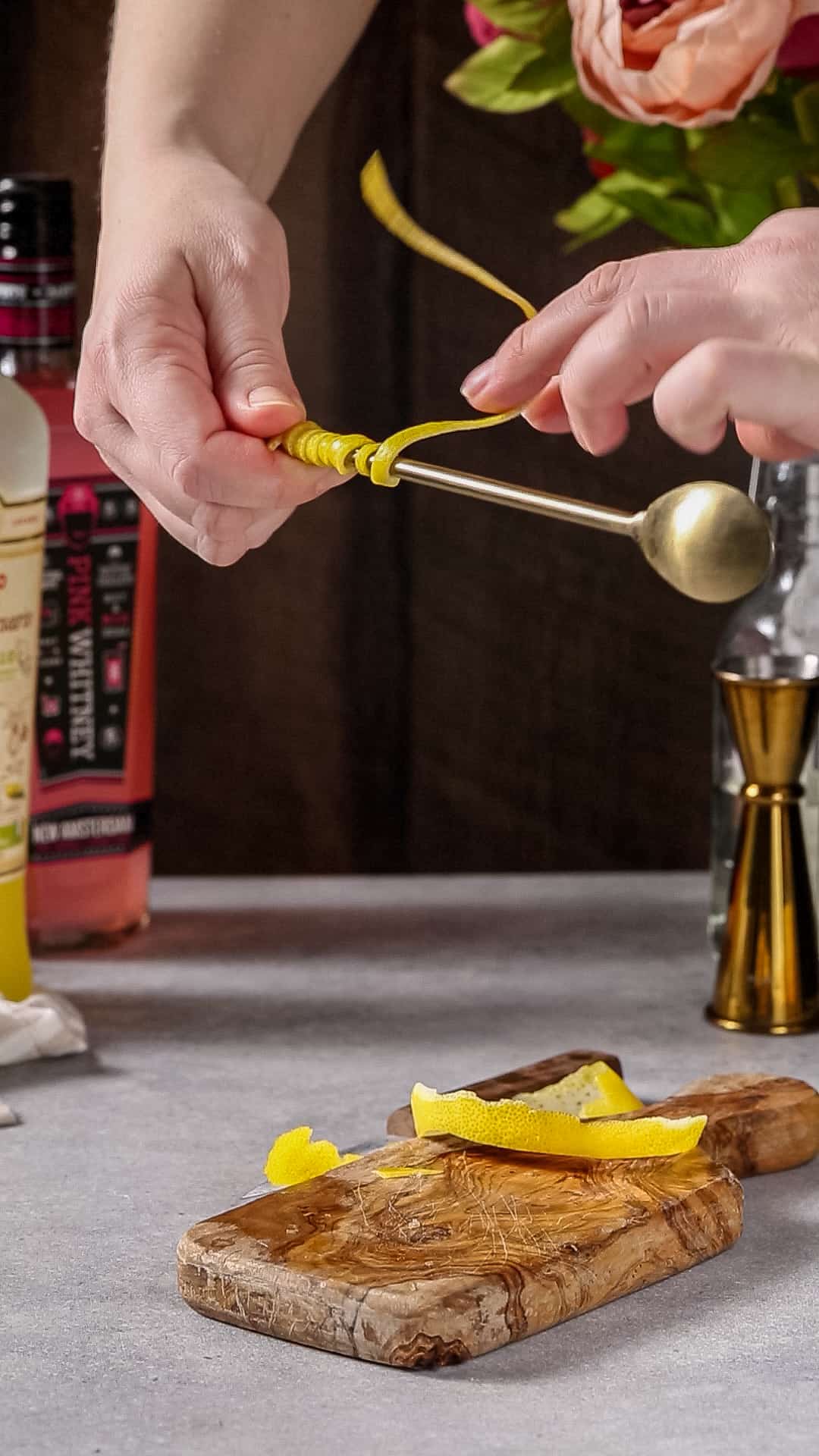 Prepping the garnish by wrapping the lemon peel around the spoon handle.