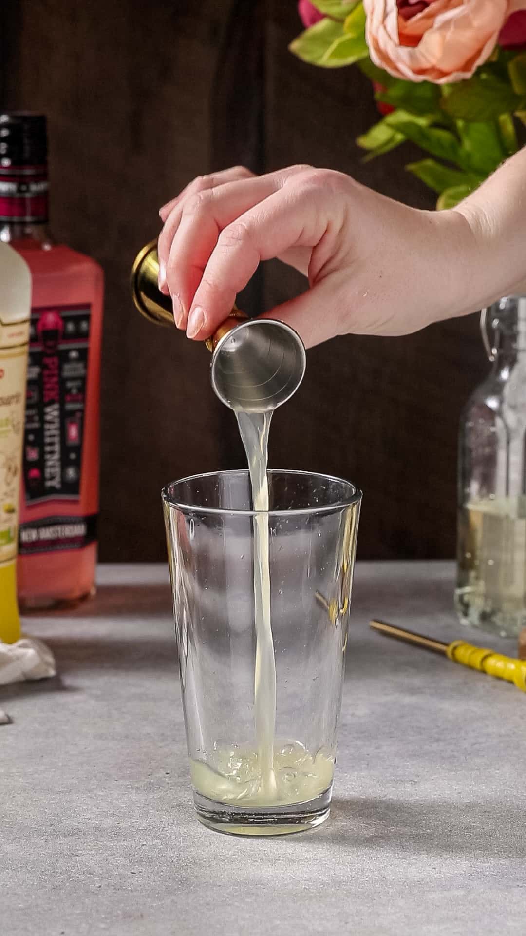 Limoncello being added to a mixing glass.