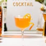 Side view of an orange colored Scofflaw Cocktail on a countertop. Ingredients and bar tools are in the background. Overlay text at the top says "Scofflaw Cocktail".