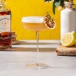 Rum sour cocktail with a dehydrated lemon clipped onto the side of the glass.