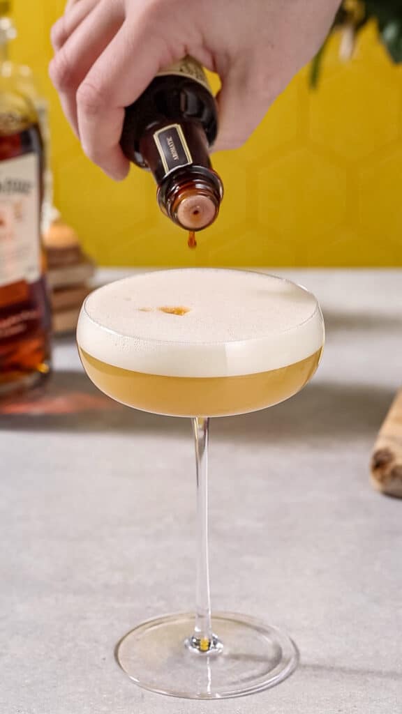 Adding drops of bitters to the top of the cocktail in the foam.