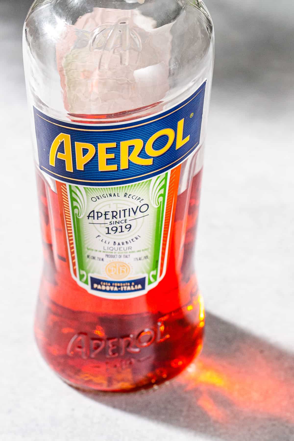 Close up of a bottle of Aperol liqueur. The bottle is half full of red liquid.
