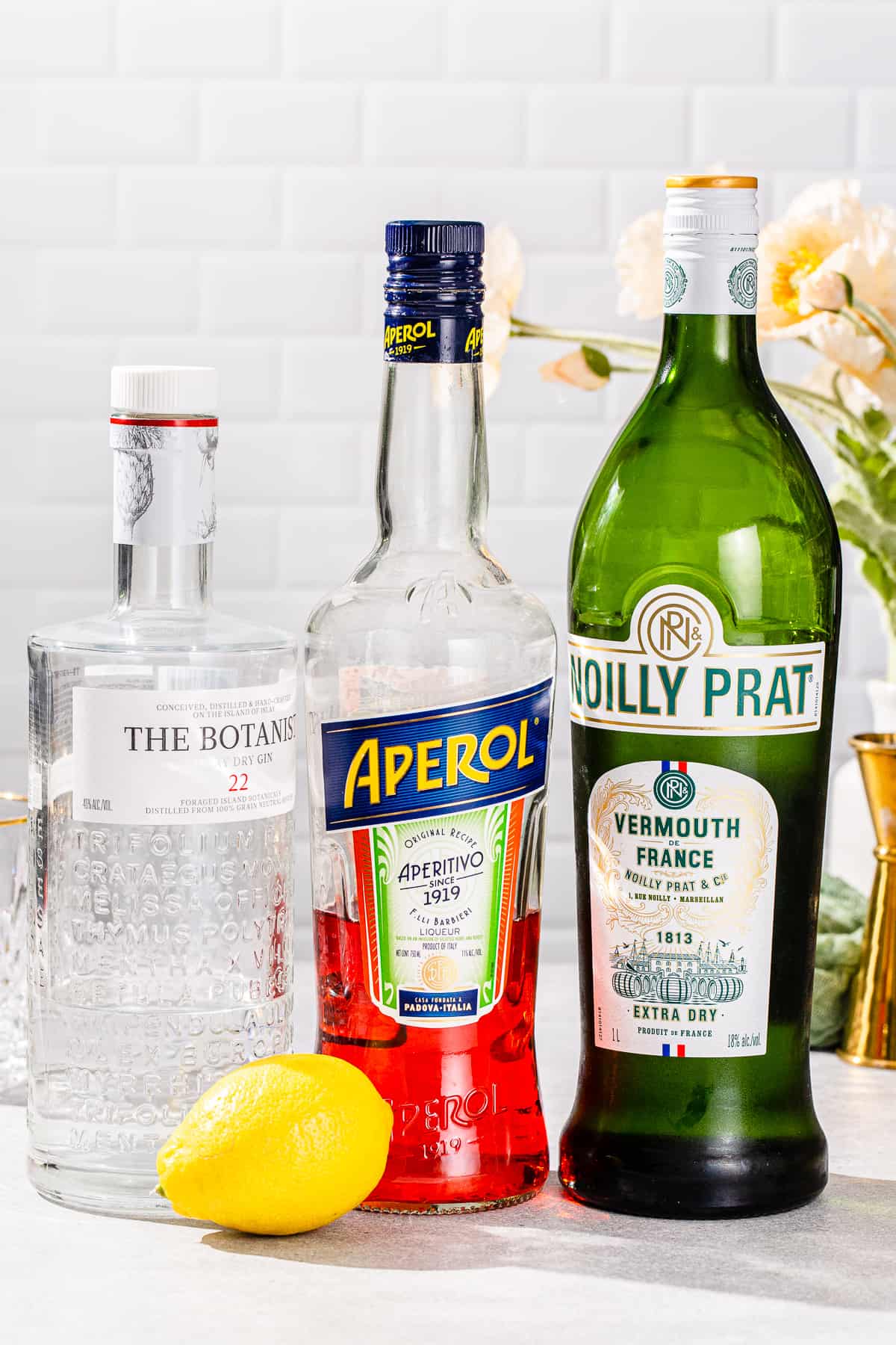 Ingredients to make an Aperol Negroni together on a countertop.