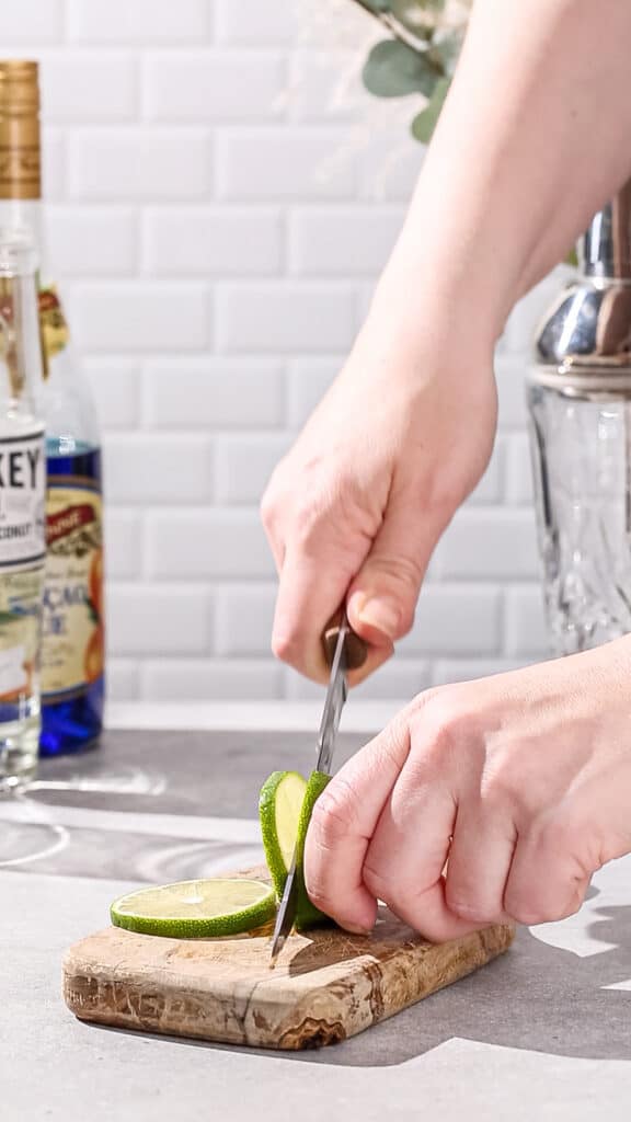 Hands cutting a slice of fresh lime.