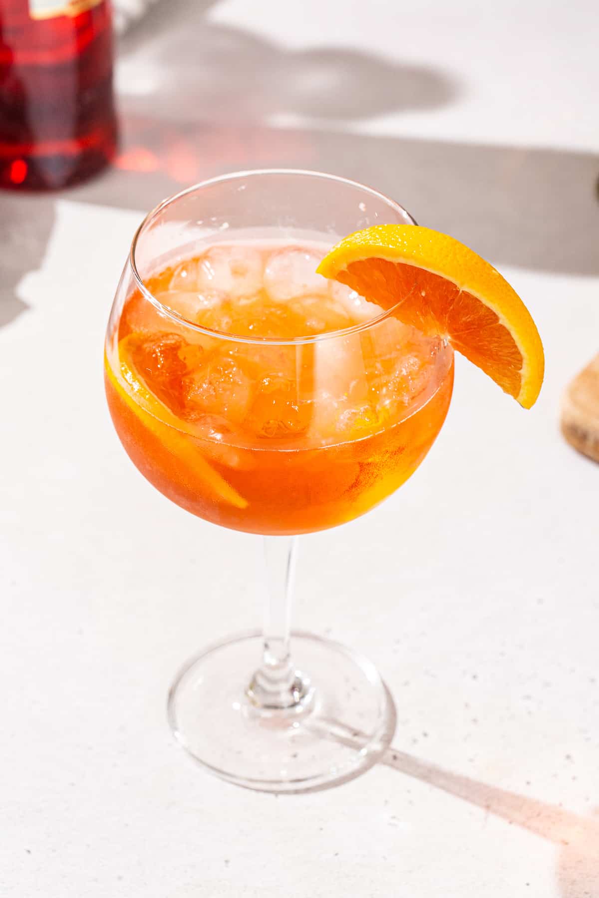 Slightly overhead view of a Negroni Spritz in a stemmed cocktail glass with orange slices as garnish.