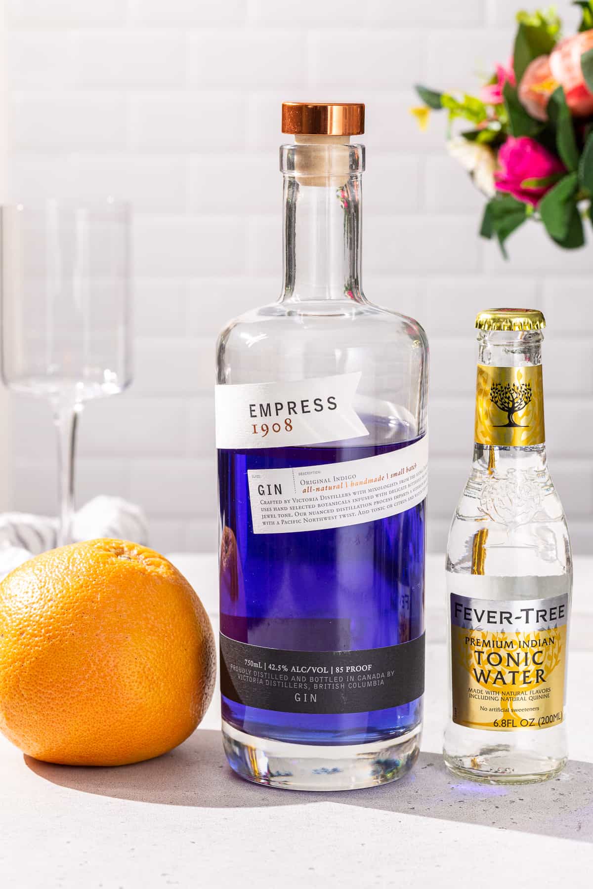 Ingredients to make an Empress Gin and Tonic cocktail together on a countertop.