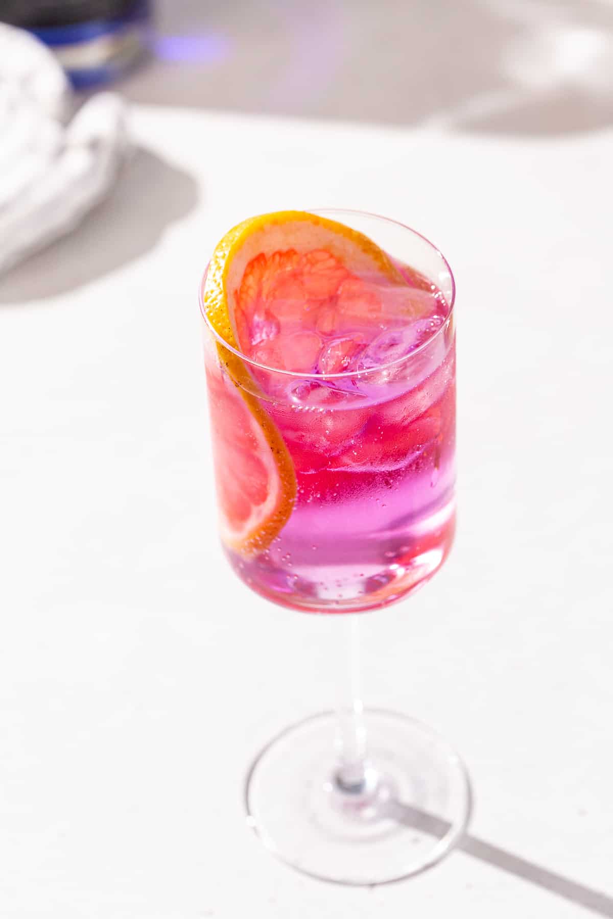 Overhead view of Empress Gin and Tonic cocktail in a wine glass. The drink is garnished with a pink grapefruit slice.