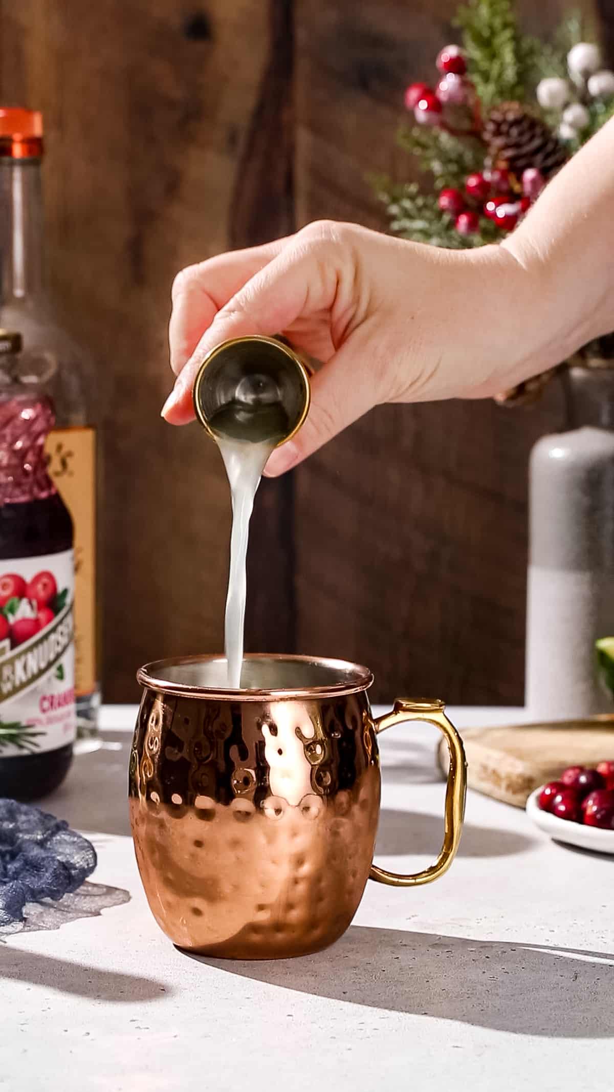 Hand pouring lime juice into a copper mug.