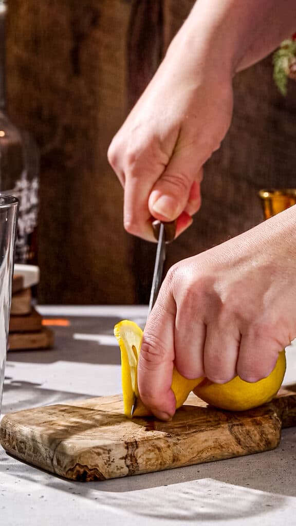 Hands cutting a slice of lemon.
