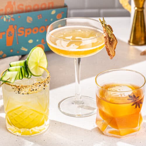 Three cocktails on a countertop with the Shaker & Spoon box in the background. These are the three cocktails you can make from the Shaker & Spoon vodka brunch box. Two are in old fashioned glasses and one is in a stemmed coupe glass.