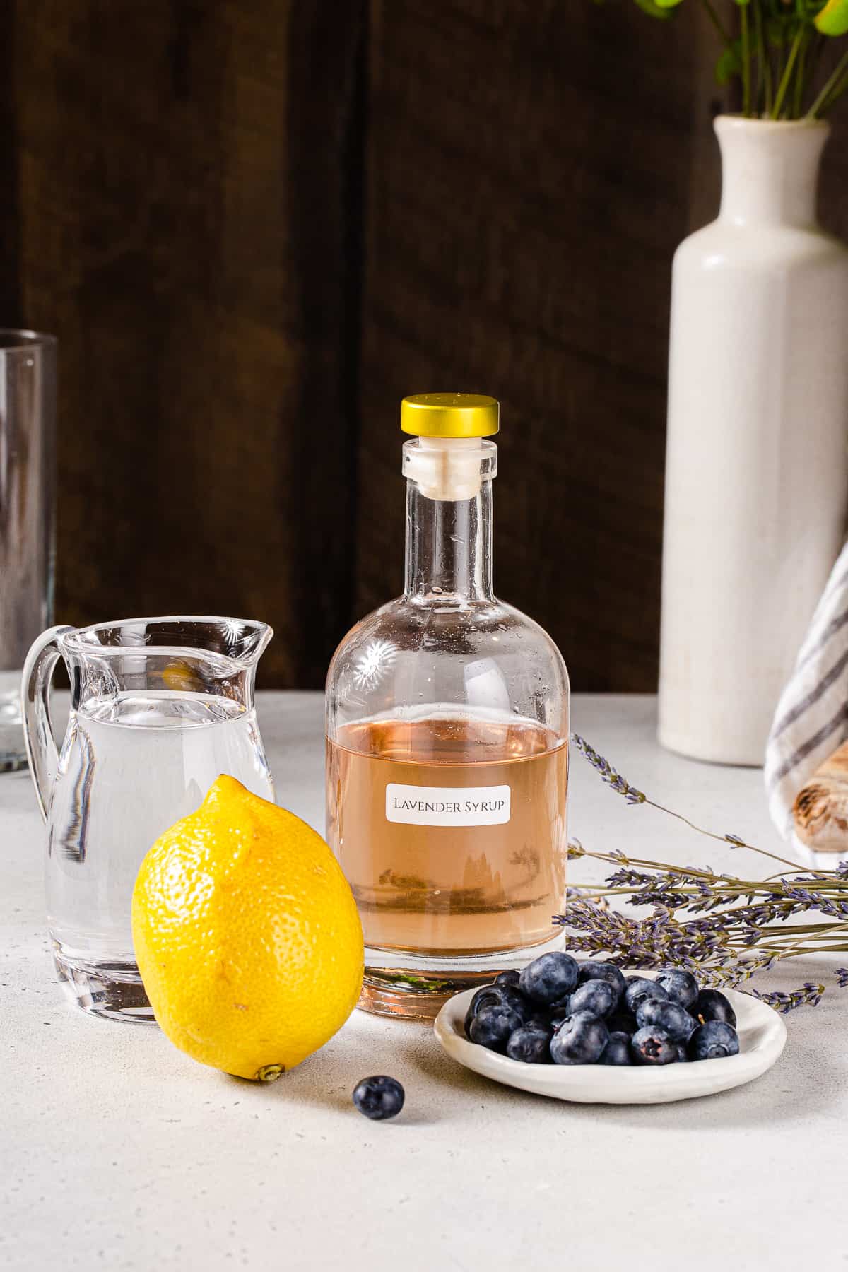 Ingredients to make a Blueberry Lavender Lemonade mocktail together on a countertop.
