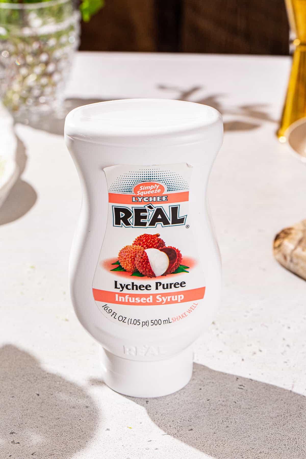 Lychee Puree on a countertop. It is in a white squeeze bottle and it is made by Real brand.