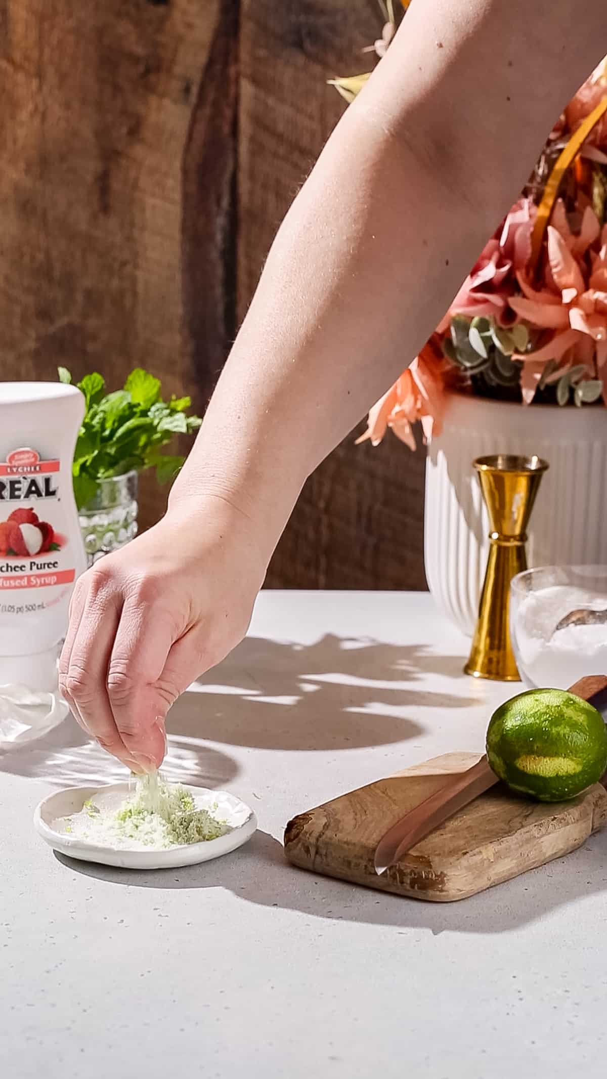 Hand mixing together lime zest and sugar in a small dish.