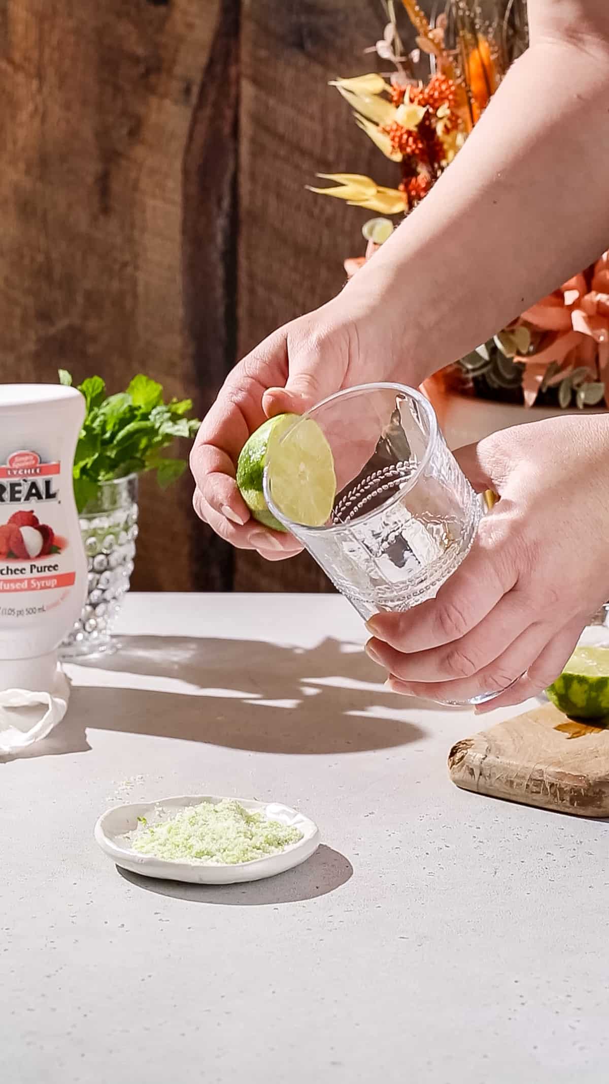 Hands wetting the rim of a cocktail glass using half a lime.