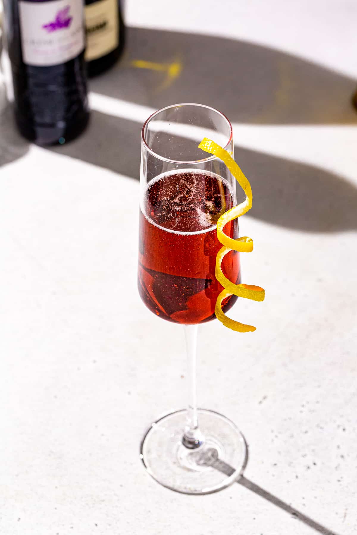 Overhead view of a Kir Royale cocktail in a champagne flute. The drink is fizzy and has a lemon peel garnish.