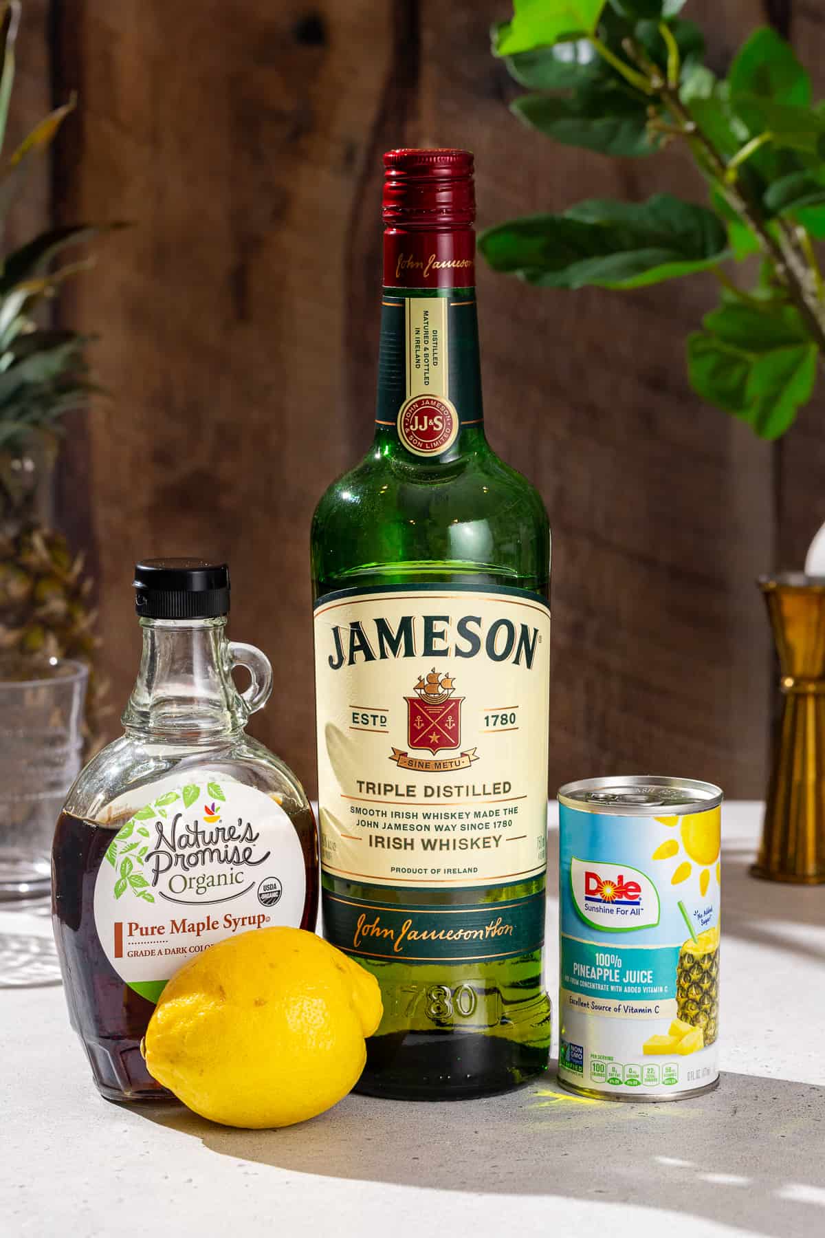 Ingredients to make a Pineapple Whiskey Sour cocktail together on a countertop.