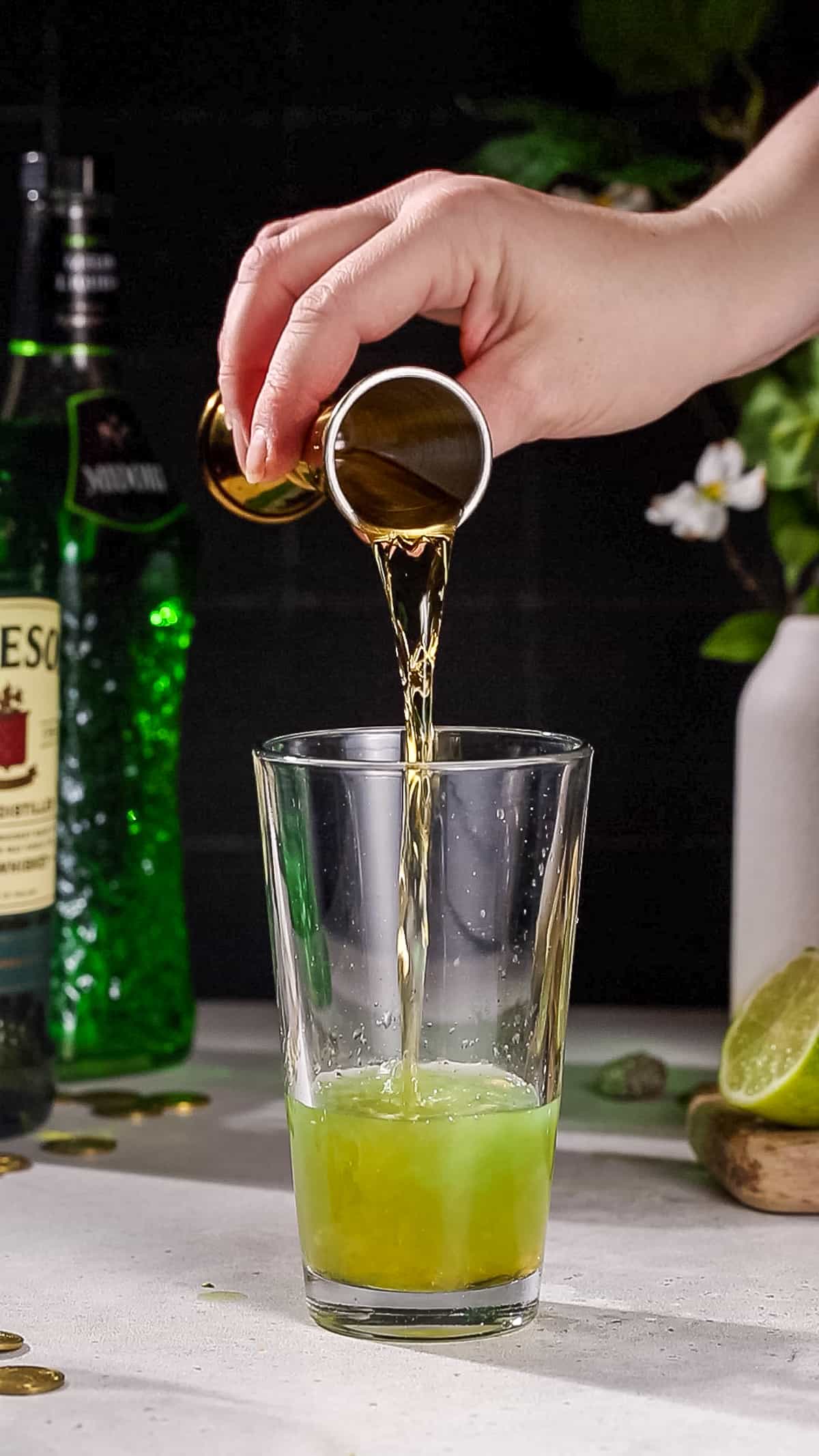 Hand adding whiskey to a cocktail shaker.