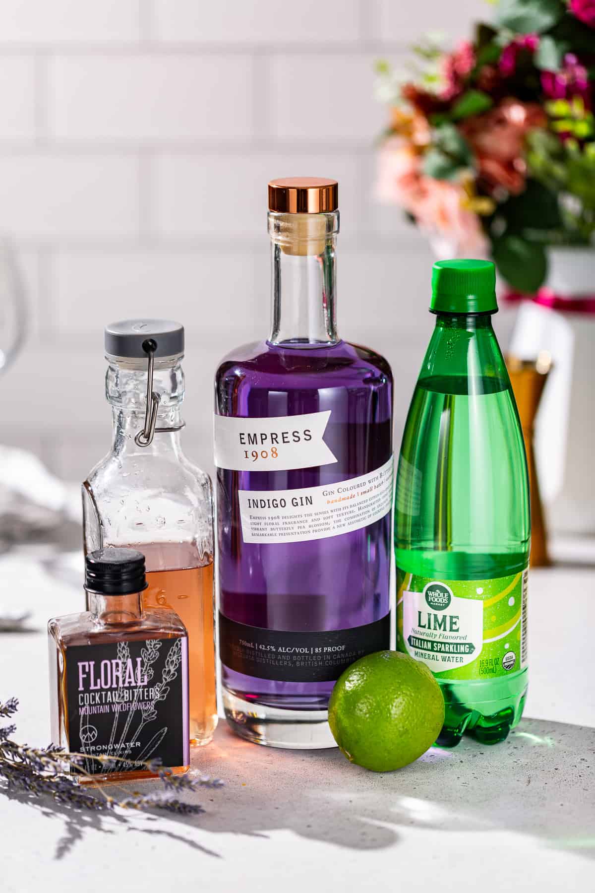 Ingredients to make a Lavender Lime gin spritz together on a countertop.