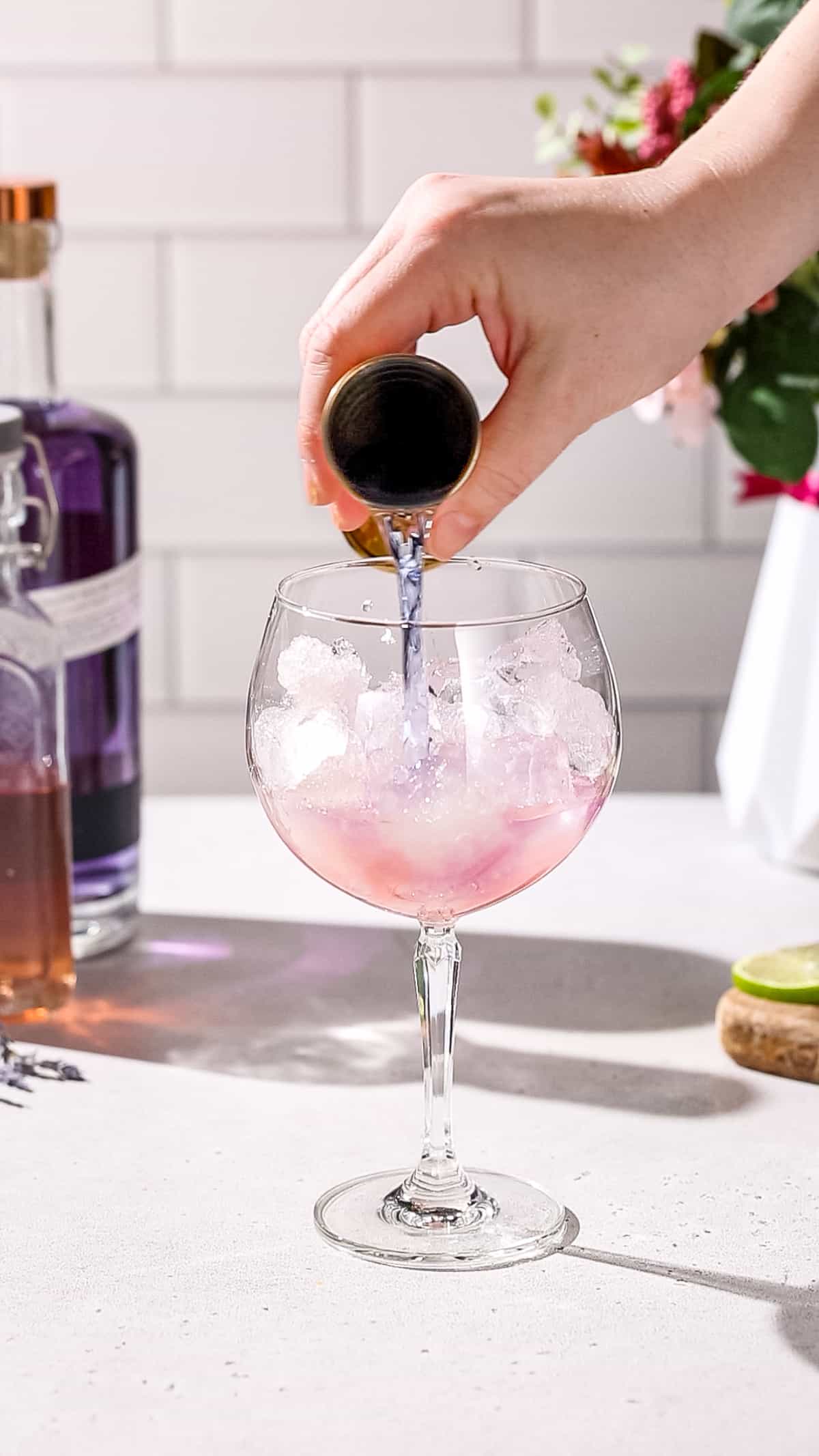 Hand adding Empress gin to a cocktail glass.