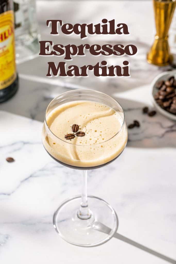 Slightly overhead shot of a Tequila Espresso Martini on a marble countertop. In the background are some ingredients and coffee beans. Text overlay at the top says “Tequila Espresso Martini”.