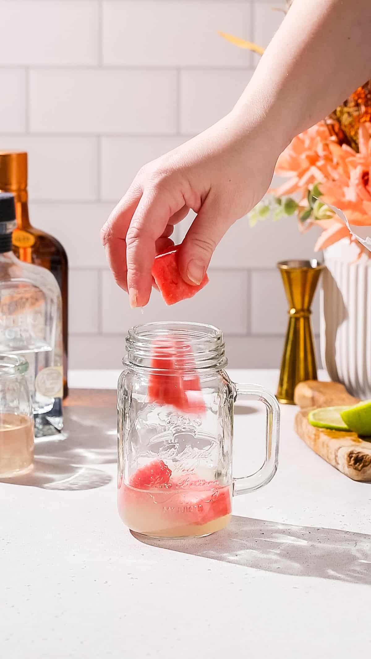 Hand adding frozen watermelon chunks to a blender cup.