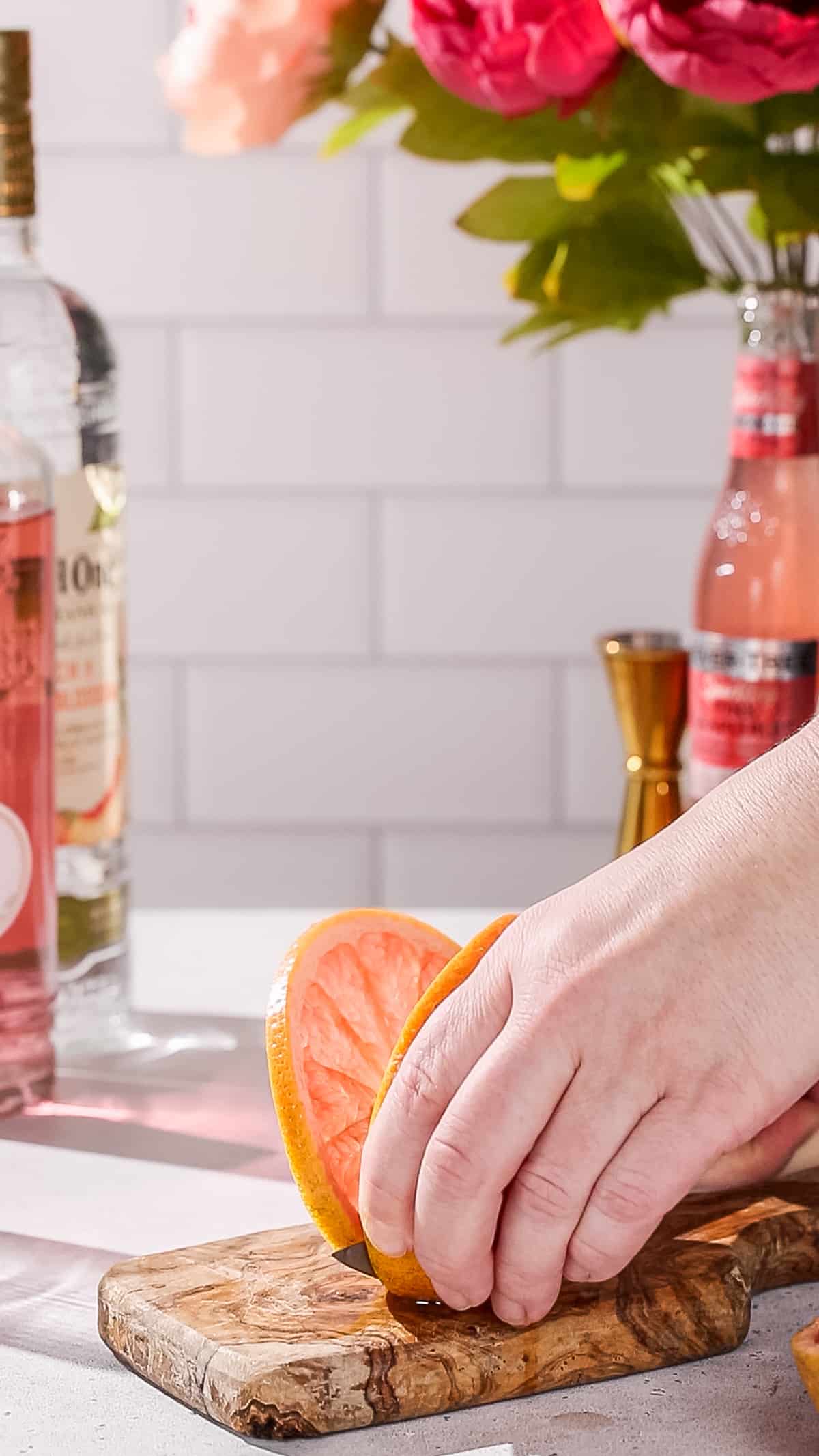 Hand cutting a slice of pink grapefruit.