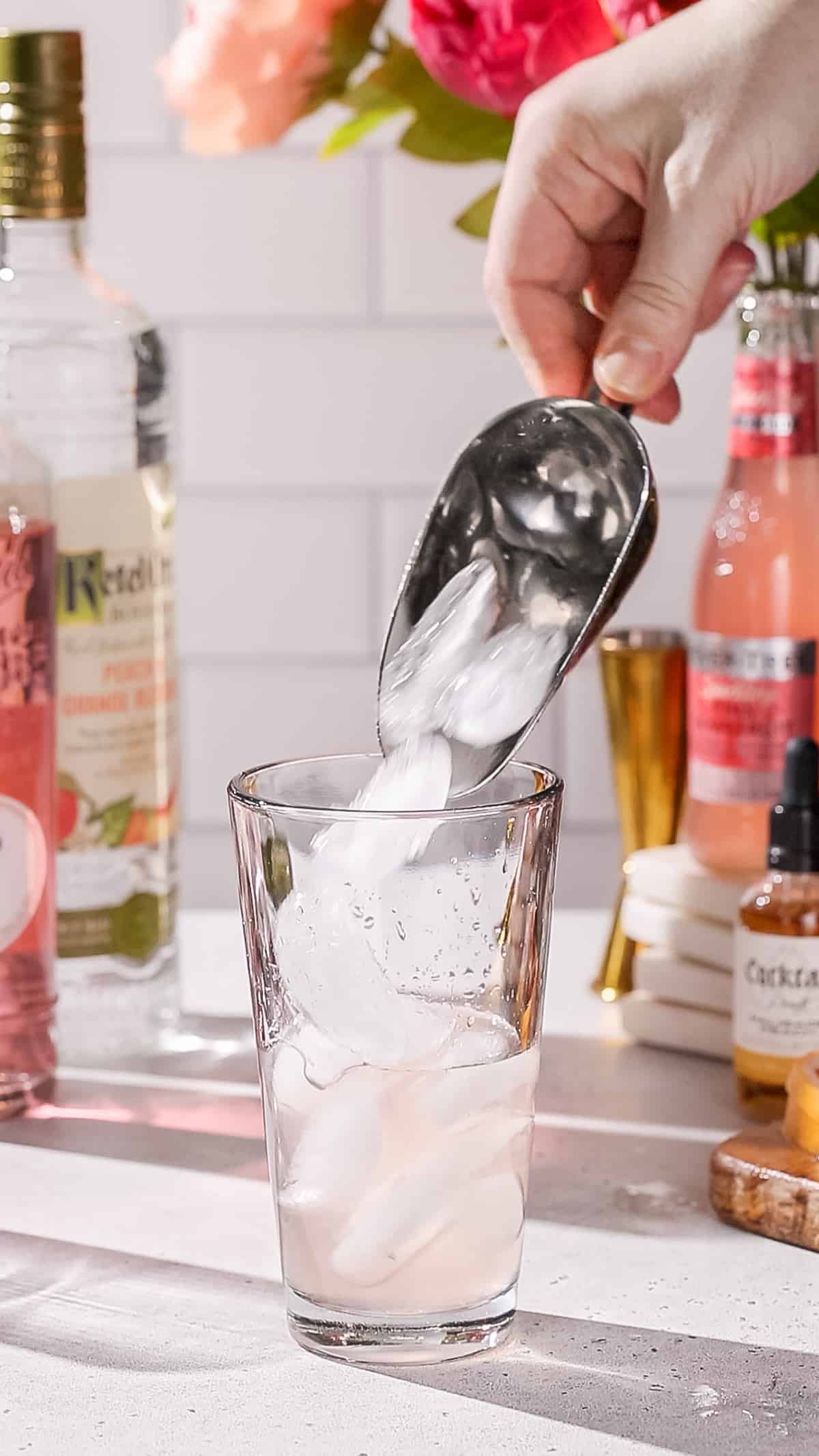 Hand adding ice to a cocktail shaker.