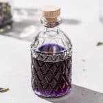 Overhead view of a bottle of purple butterfly pea tequila on a countertop.