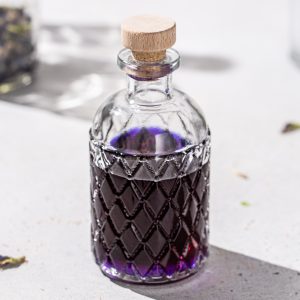 Overhead view of a bottle of purple butterfly pea tequila on a countertop.