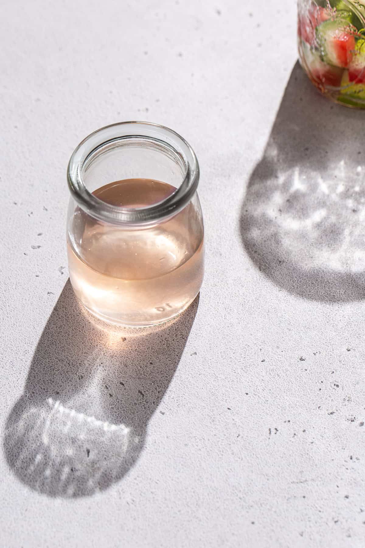 Overhead view of a jar of pink watermelon rind syrup.