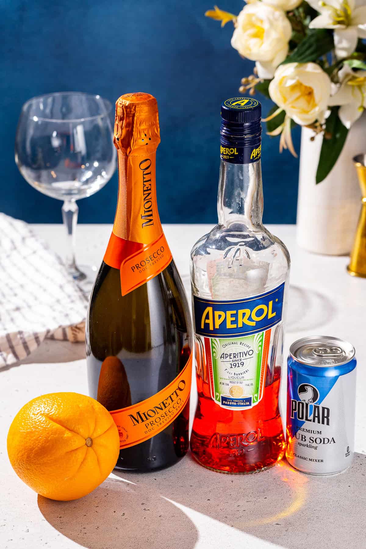 Ingredients to make an Aperol Spritz cocktail together on a countertop.