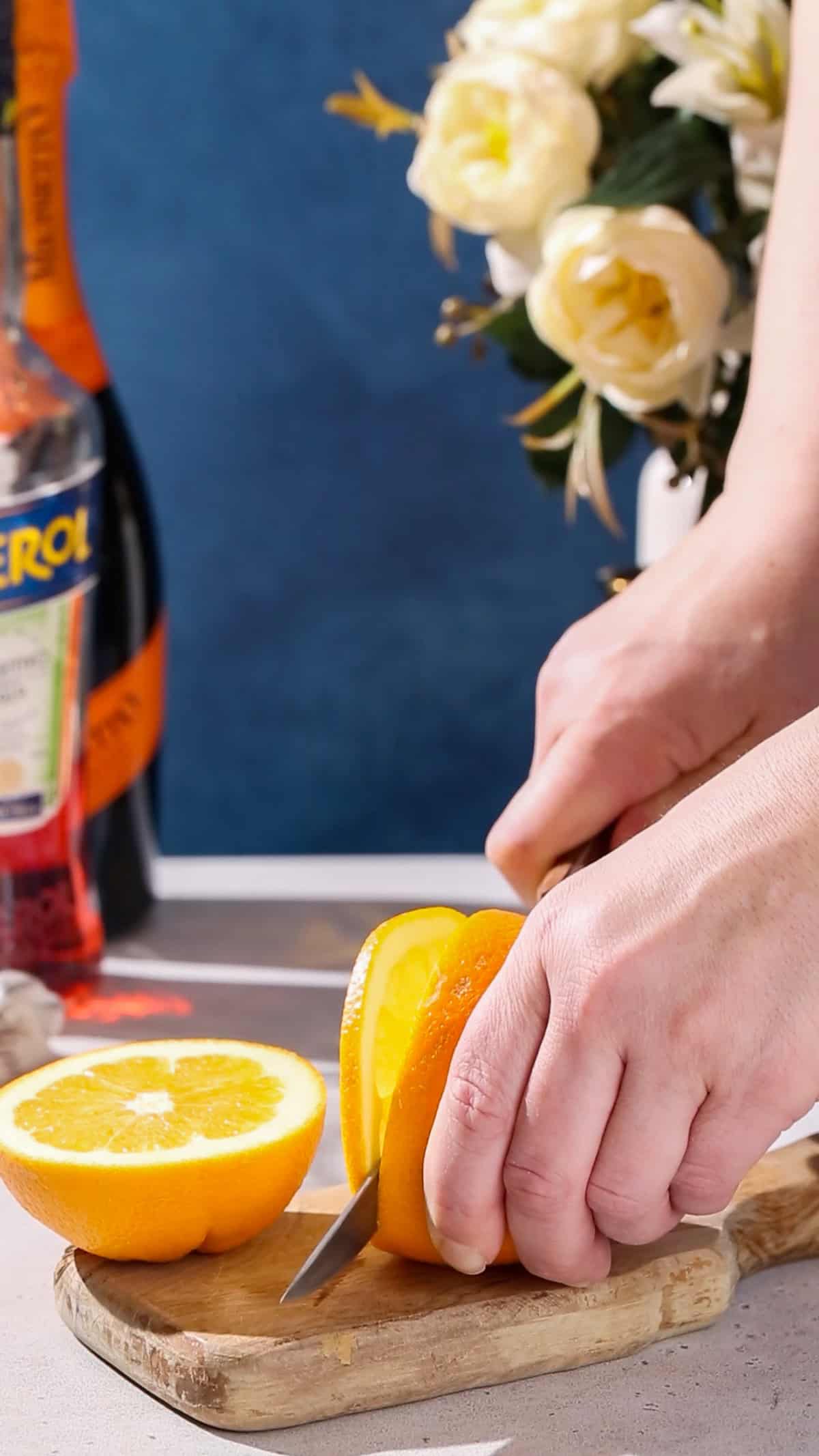 Hands cutting a slice of an orange.