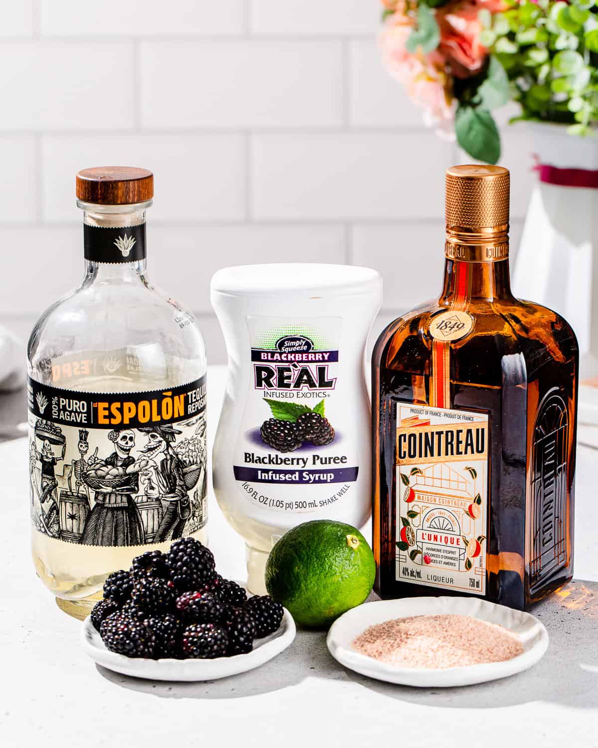 Ingredients to make a Blackberry Margarita recipe together on a countertop.