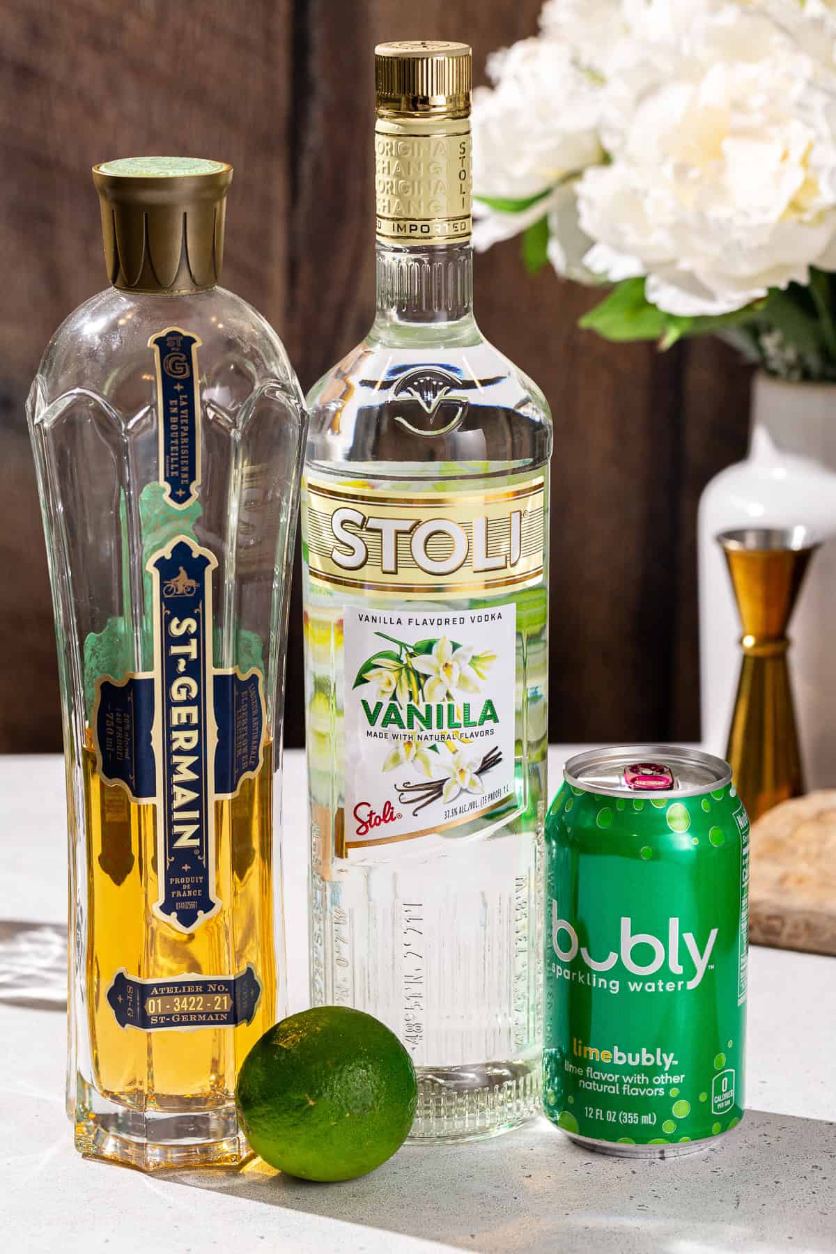 Ingredients to make a Vanilla Lime Vodka Refresher together on a countertop.