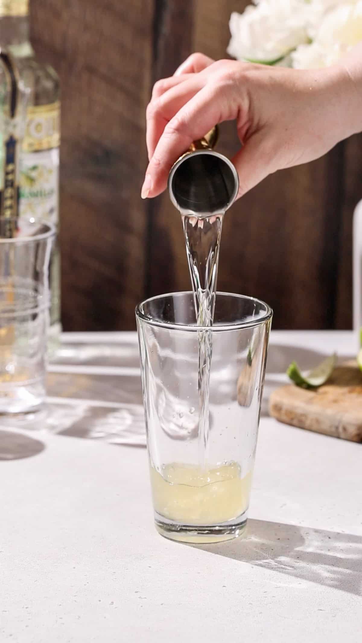 Hand pouring vanilla vodka into a cocktail shaker.