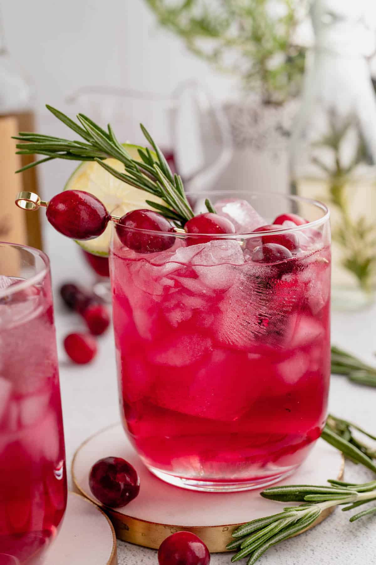 Red cocktails with cranberry and rosemary garnish.