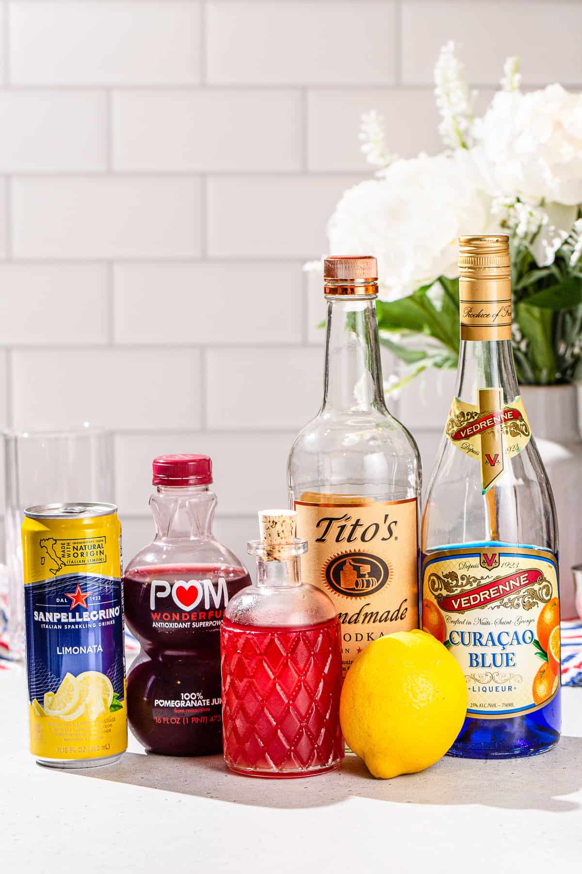 Ingredients used to make a layered Red White and Blue Cocktail all together on a countertop.