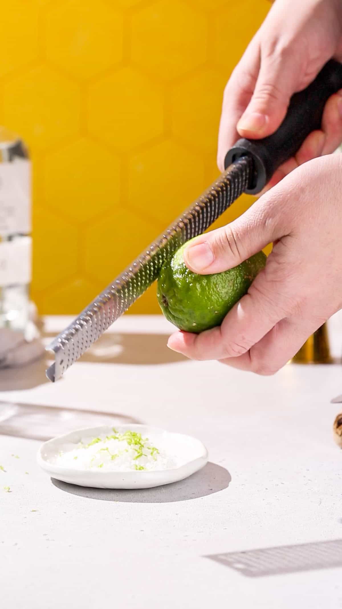 Hands using a zest grater to zest a lime.