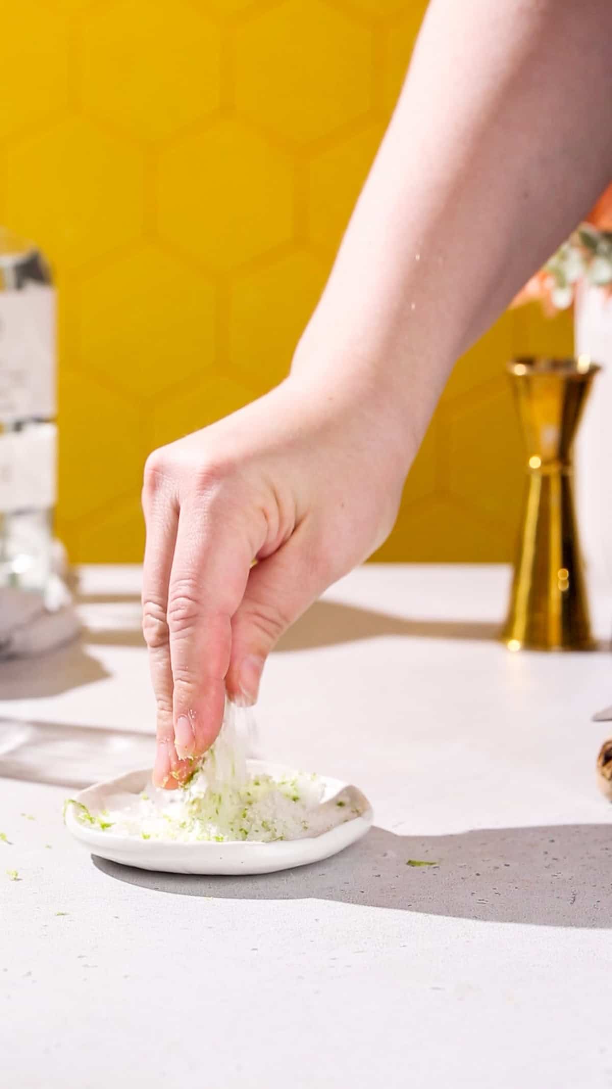 Hand mixing together rim salt and lime zest in a small dish.