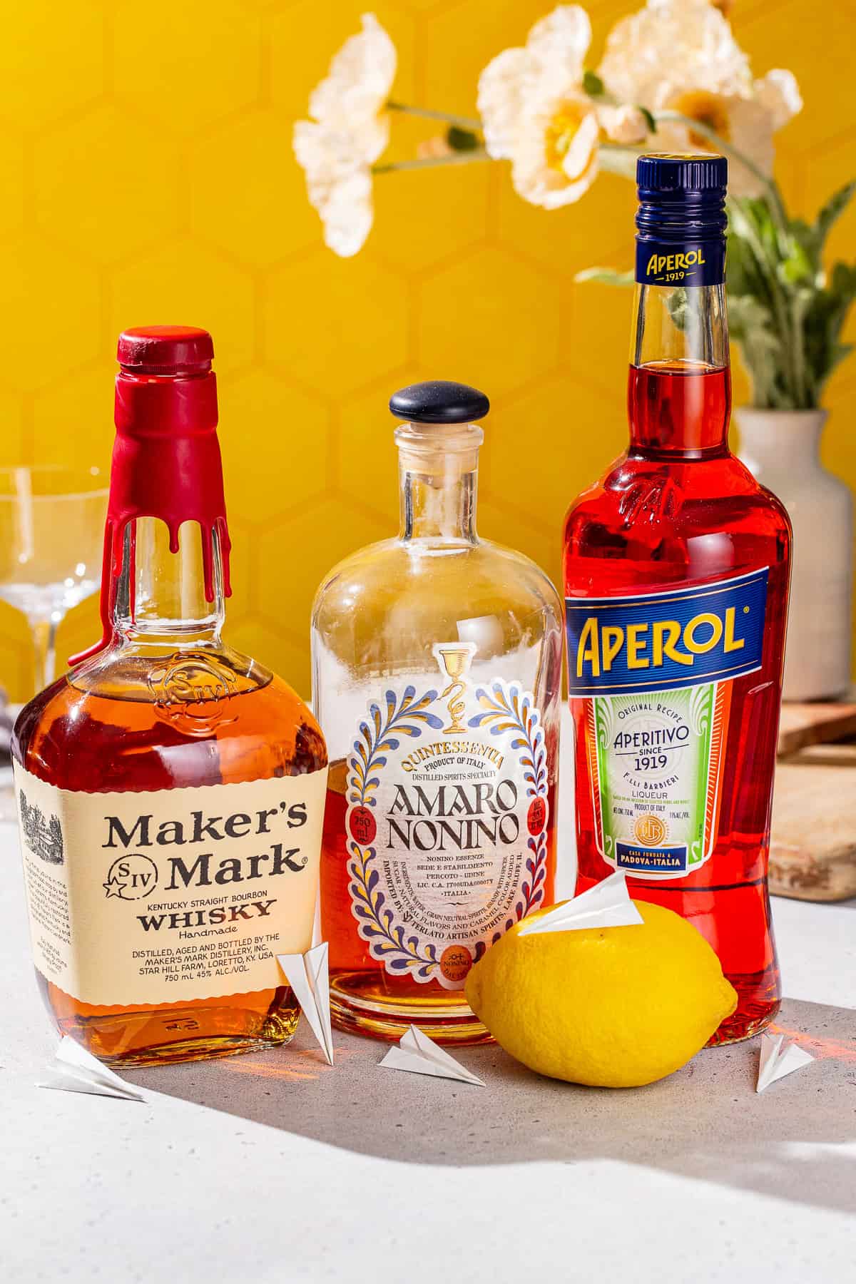 Ingredients to make a Paper Plane cocktail together on a countertop.