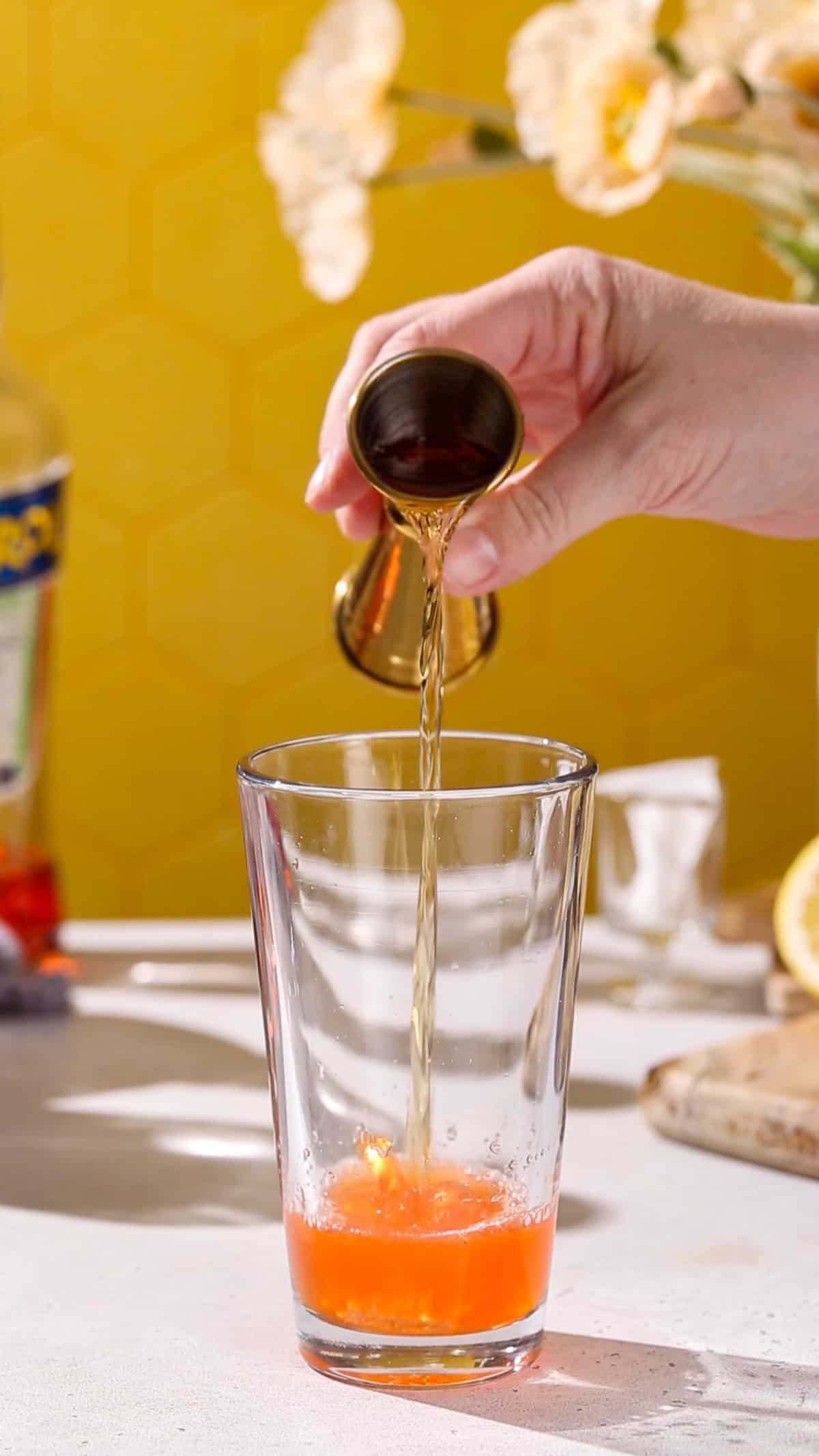 Hand adding Amaro Nonino to a cocktail shaker.