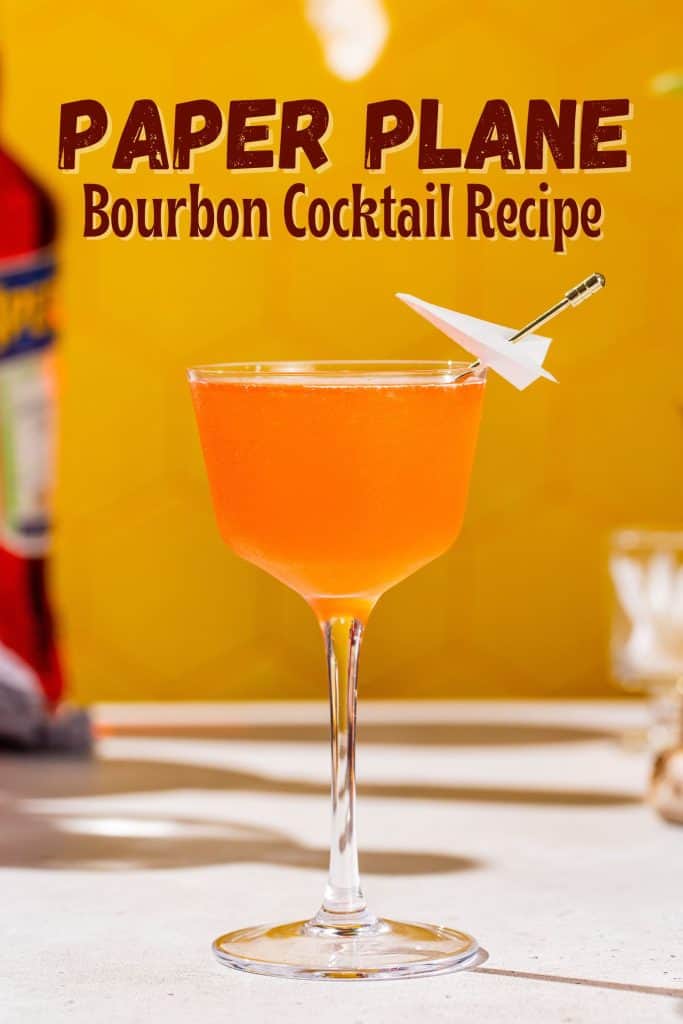 Side view of a Paper Plane cocktail in a coupe glass with a mini paper plane as a garnish. Text at the top of the image says “paper plane bourbon cocktail recipe”.